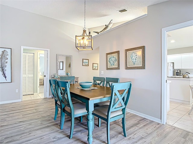 542 Clubside Cir Unit 20, Venice, FL 34293 - dining space featuring a textured ceiling, light wood-style flooring, visible vents, baseboards, and a notable chandelier