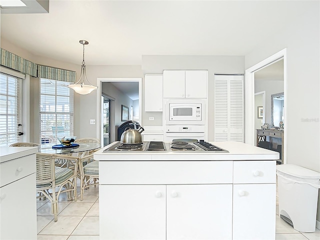 542 Clubside Cir Unit 20, Venice, FL 34293 - kitchen featuring light tile patterned floors, white cabinetry, decorative light fixtures, stainless steel stovetop, and white microwave