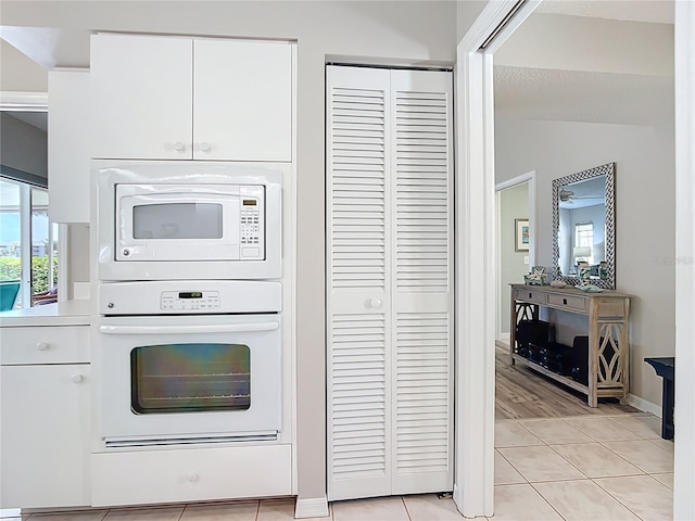 542 Clubside Cir Unit 20, Venice, FL 34293 - kitchen with white appliances, light tile patterned floors, light countertops, white cabinets, and baseboards