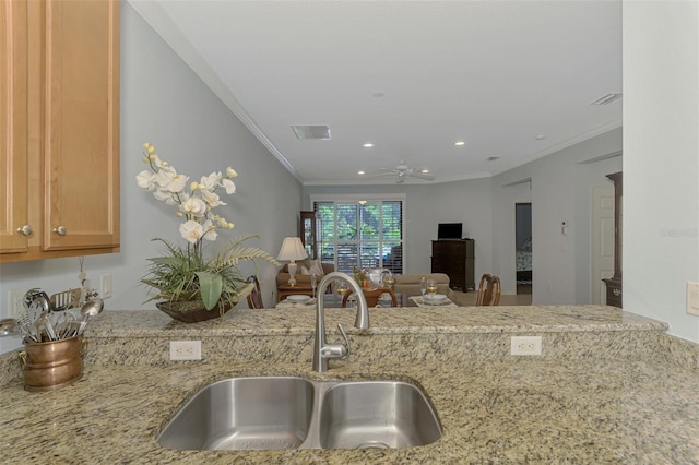 kitchen featuring crown molding, visible vents, ceiling fan, light stone counters, and a sink