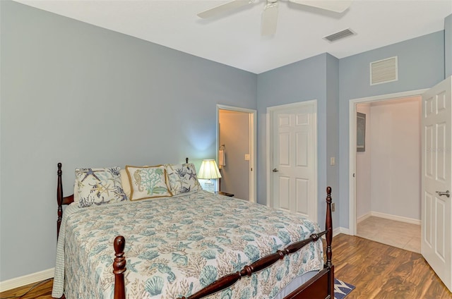 bedroom with baseboards, visible vents, and wood finished floors