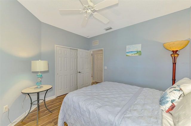 bedroom with ceiling fan, baseboards, wood finished floors, visible vents, and a closet