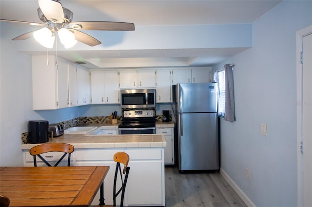 400 Base Unit 225, Venice, FL 34293 - kitchen featuring stainless steel appliances, tile counters, a peninsula, a sink, and a ceiling fan