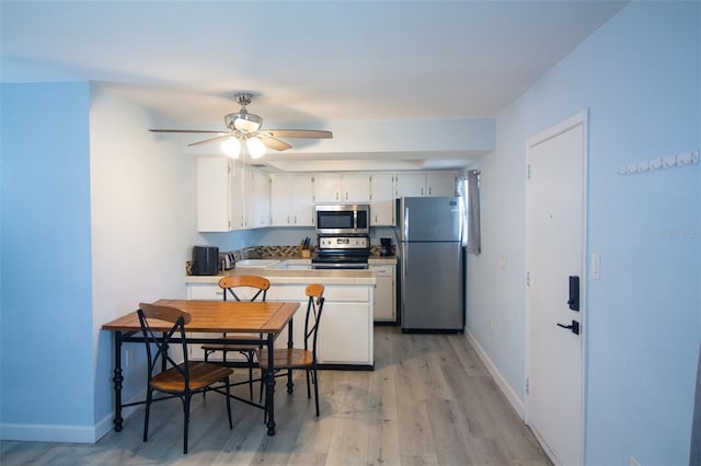 400 Base Unit 225, Venice, FL 34293 - kitchen with appliances with stainless steel finishes, light wood-type flooring, white cabinets, a peninsula, and baseboards