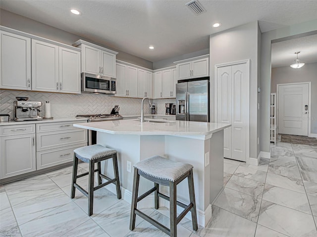220 Sarezzo Cir, Nokomis, FL 34275 - kitchen with appliances with stainless steel finishes, a sink, light marble finish floors, a kitchen breakfast bar, and backsplash