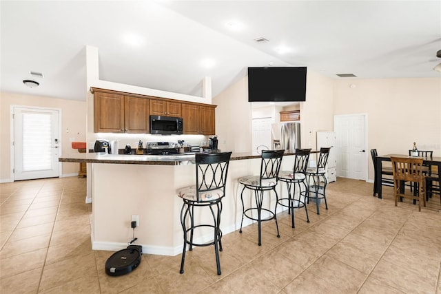 14124 Kewanee Ln, Port Charlotte, FL 33981 - kitchen featuring a kitchen breakfast bar, appliances with stainless steel finishes, dark countertops, light tile patterned flooring, and vaulted ceiling