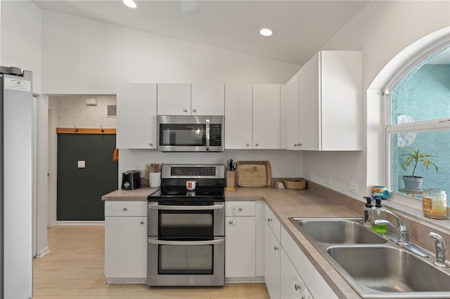 5264 Albion Rd, Venice, FL 34293 - kitchen featuring stainless steel appliances, light countertops, vaulted ceiling, white cabinets, and a sink