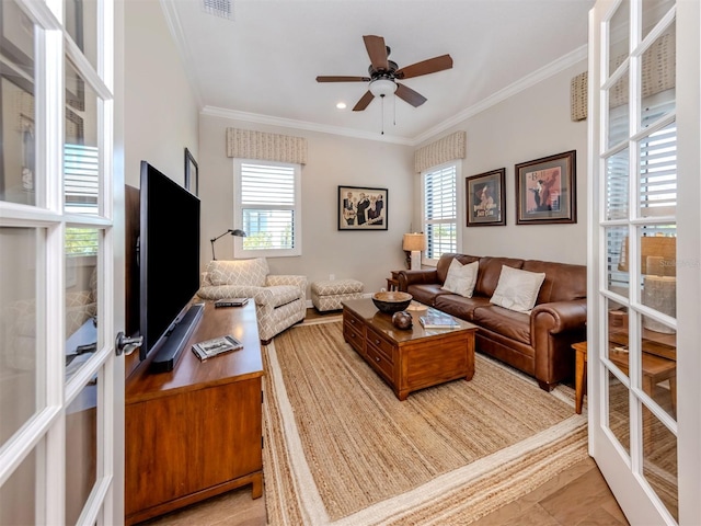 living area with a wealth of natural light, ceiling fan, and ornamental molding