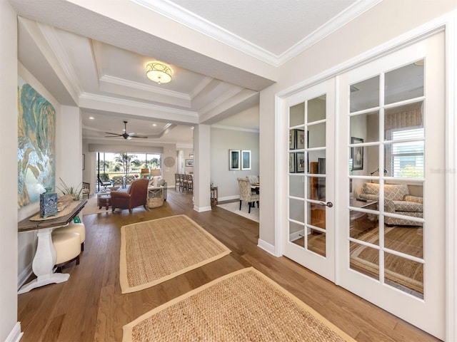interior space with french doors, wood finished floors, ornamental molding, and a raised ceiling