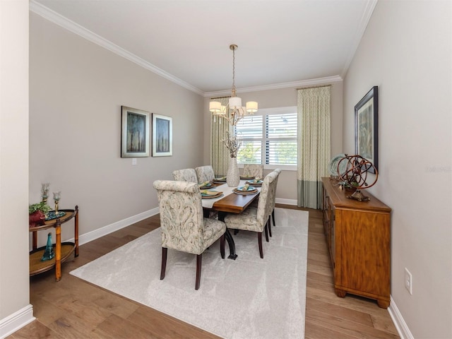 dining area featuring light wood-type flooring, ornamental molding, and an inviting chandelier