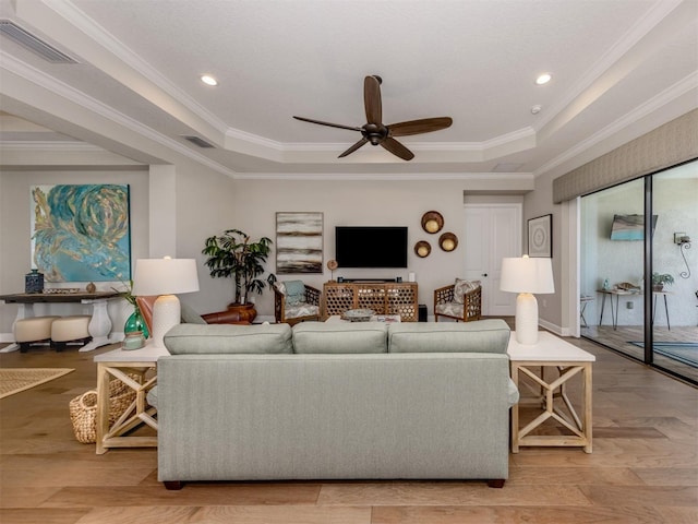 living area featuring a ceiling fan, visible vents, and a raised ceiling