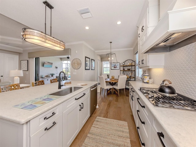 kitchen with a sink, visible vents, stainless steel appliances, light wood-style floors, and premium range hood