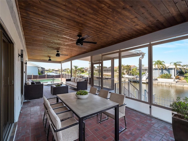sunroom / solarium with ceiling fan, a water view, and an outdoor living space
