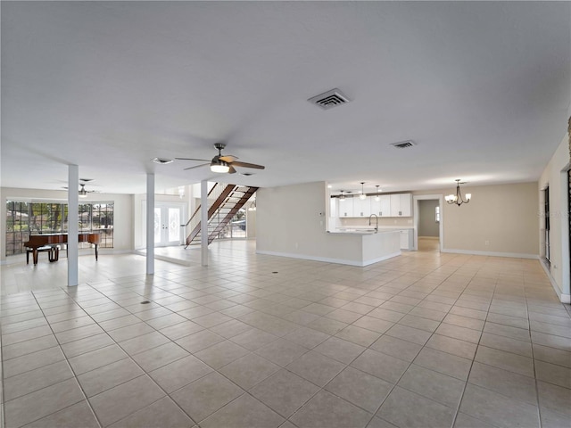 unfurnished living room with light tile patterned floors, visible vents, baseboards, and ceiling fan with notable chandelier