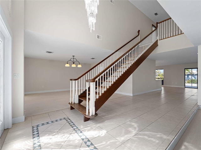 staircase featuring a high ceiling, visible vents, and a chandelier