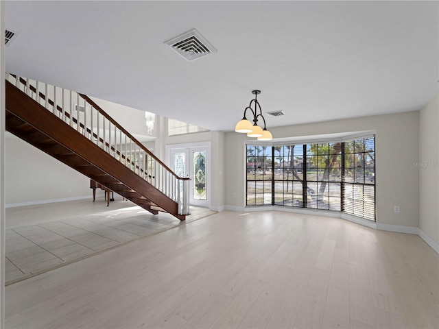 unfurnished living room featuring plenty of natural light, visible vents, wood finished floors, and baseboards
