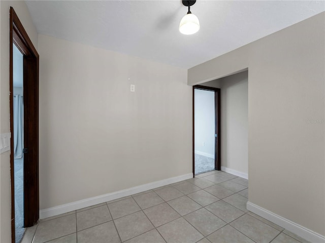 empty room with light tile patterned flooring and baseboards