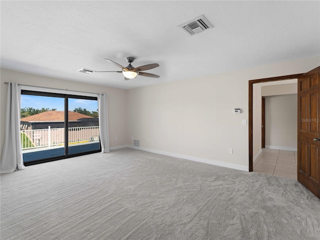spare room featuring a ceiling fan, visible vents, and light colored carpet