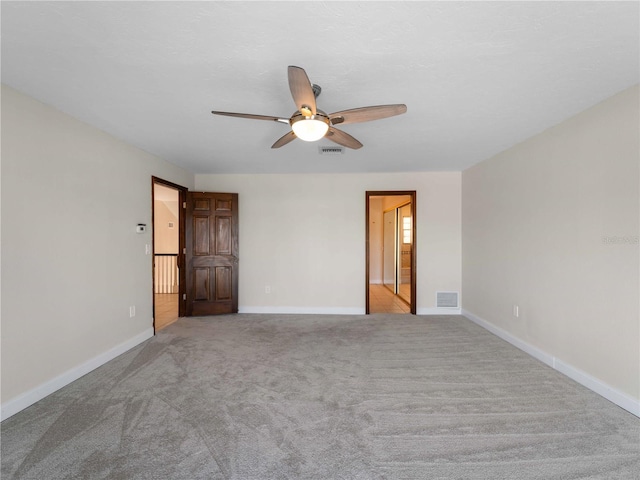 unfurnished room with carpet, visible vents, a ceiling fan, and baseboards