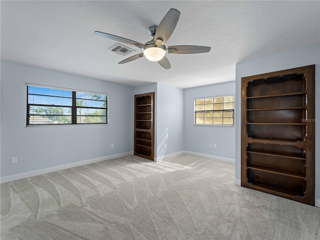 unfurnished bedroom featuring baseboards, visible vents, ceiling fan, and carpet