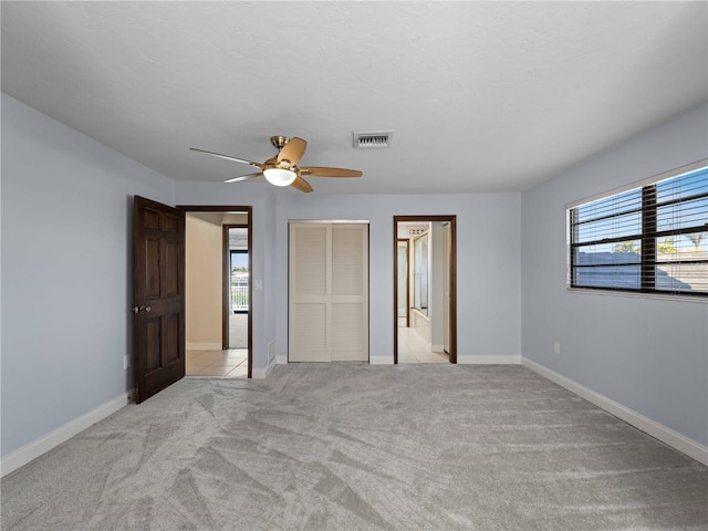 unfurnished bedroom featuring baseboards, a ceiling fan, visible vents, and light carpet
