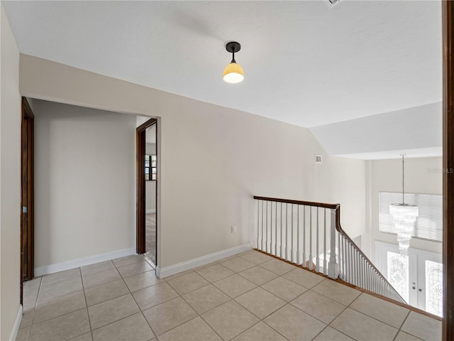 spare room with light tile patterned flooring, a chandelier, plenty of natural light, and baseboards