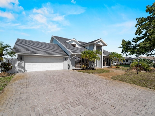 view of front of property with a front lawn, a garage, decorative driveway, a tiled roof, and stucco siding