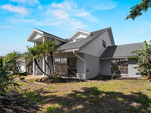 view of side of property featuring a tile roof, a lawn, and brick siding