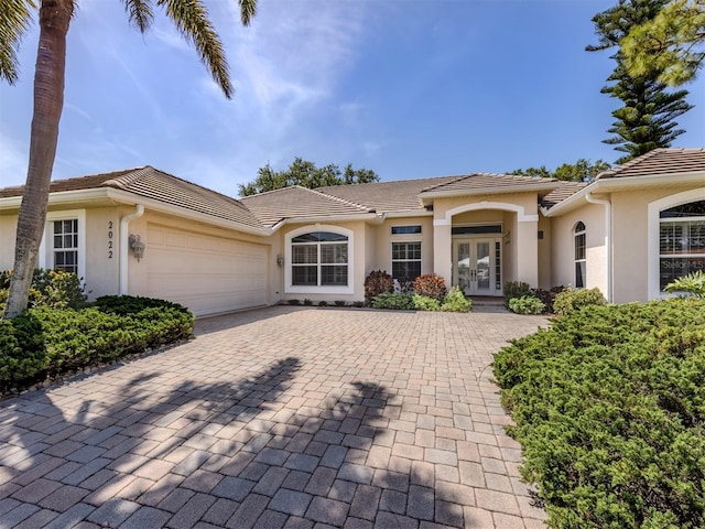 2022 Calusa Lakes Blvd, Nokomis, FL 34275 - view of front of home featuring stucco siding, a tiled roof, decorative driveway, french doors, and an attached garage