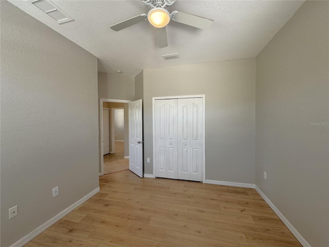 unfurnished bedroom with light wood finished floors, a closet, visible vents, and baseboards