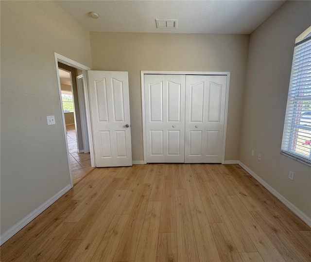 unfurnished bedroom with multiple windows, visible vents, baseboards, and light wood-style floors