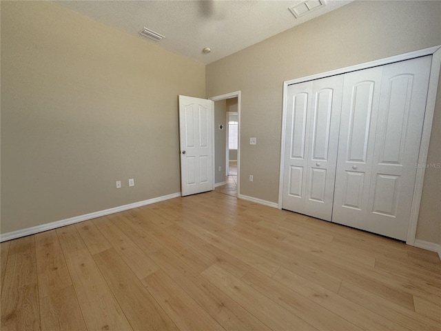 unfurnished bedroom featuring baseboards, visible vents, a closet, and light wood finished floors