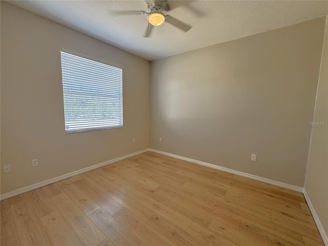 spare room with baseboards, ceiling fan, and light wood-style floors