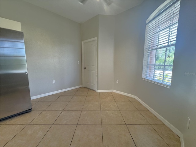 spare room with light tile patterned floors, ceiling fan, and baseboards