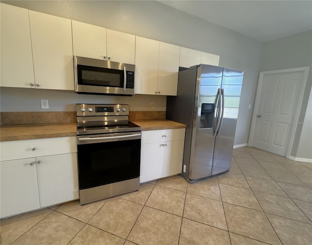 kitchen with light tile patterned flooring, white cabinets, stainless steel appliances, and light countertops