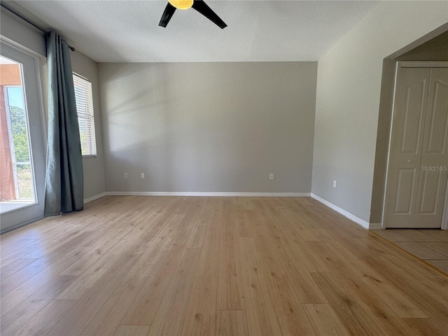 empty room featuring a ceiling fan, baseboards, and light wood-style floors