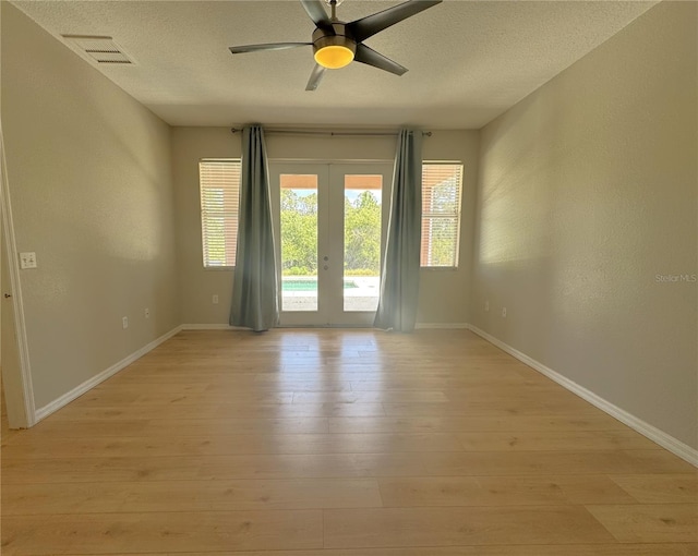unfurnished room featuring a textured ceiling, visible vents, light wood-style flooring, and french doors