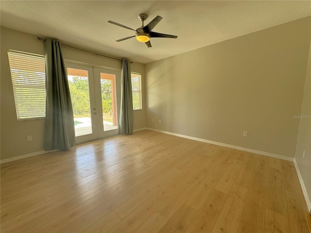 unfurnished room featuring a textured ceiling, french doors, a ceiling fan, and light wood-style floors