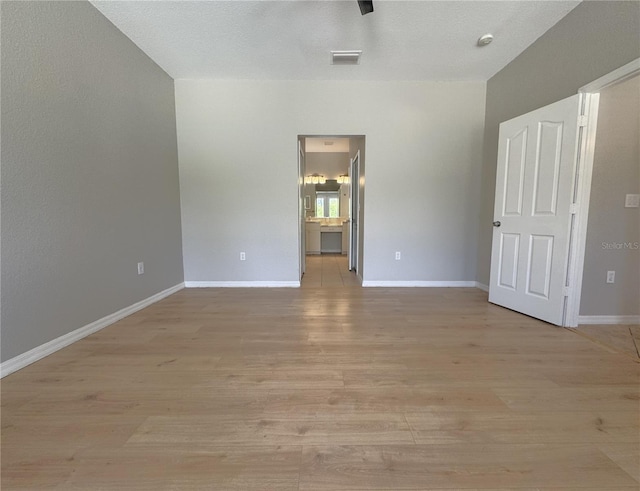 unfurnished bedroom featuring ensuite bath, visible vents, light wood-style flooring, and baseboards