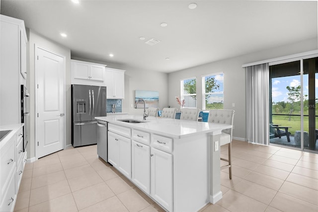 kitchen with recessed lighting, stainless steel appliances, a kitchen bar, a sink, and light tile patterned flooring