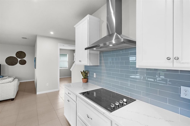 kitchen with decorative backsplash, black electric cooktop, white cabinets, baseboards, and wall chimney exhaust hood