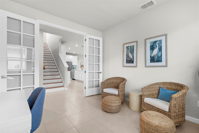 living area featuring light tile patterned floors, visible vents, baseboards, french doors, and stairs