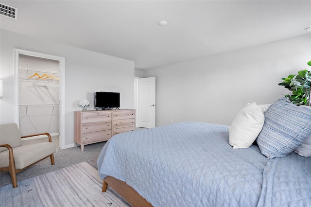 bedroom featuring a closet, a walk in closet, visible vents, baseboards, and light colored carpet