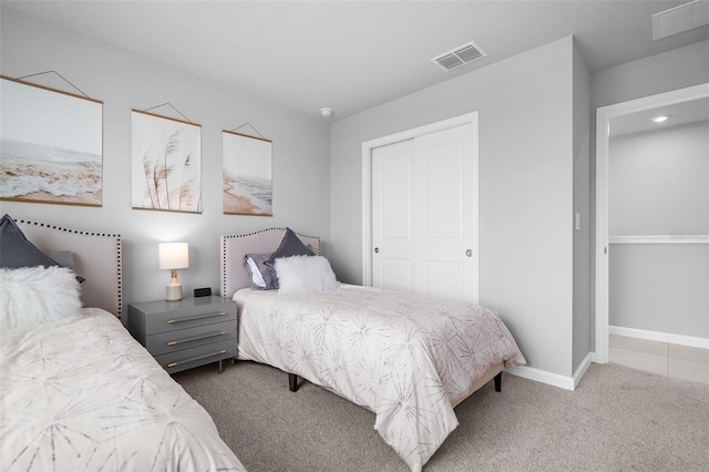 carpeted bedroom featuring visible vents, a closet, and baseboards
