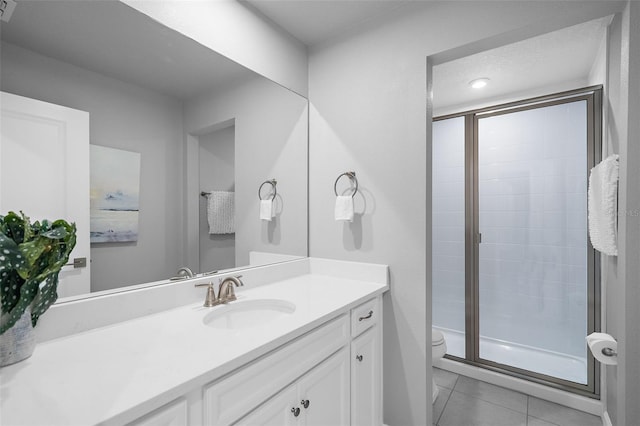 full bathroom featuring toilet, a stall shower, tile patterned flooring, and vanity