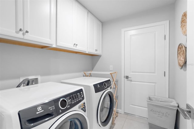 laundry area featuring light tile patterned flooring, washer and clothes dryer, and cabinet space