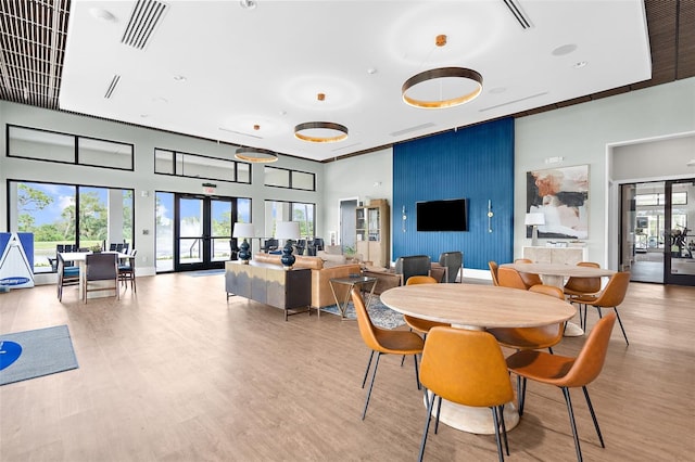 dining area with french doors, light wood-style floors, visible vents, and a high ceiling