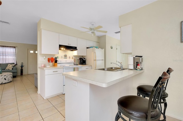 kitchen featuring a sink, white appliances, light countertops, a peninsula, and a kitchen bar