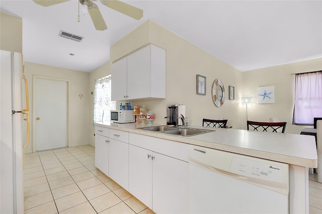 kitchen with visible vents, a peninsula, white appliances, light countertops, and a sink