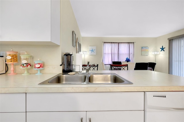 kitchen with white dishwasher, white cabinets, and light countertops